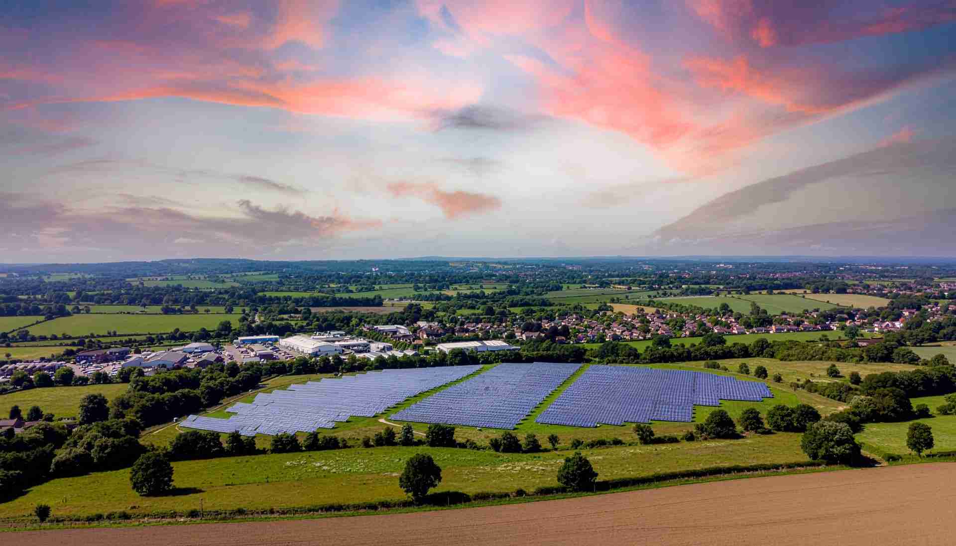 Wide cinematic view of a British landscape with rolling green hills and a market town — representing UK commercial energy infrastructure