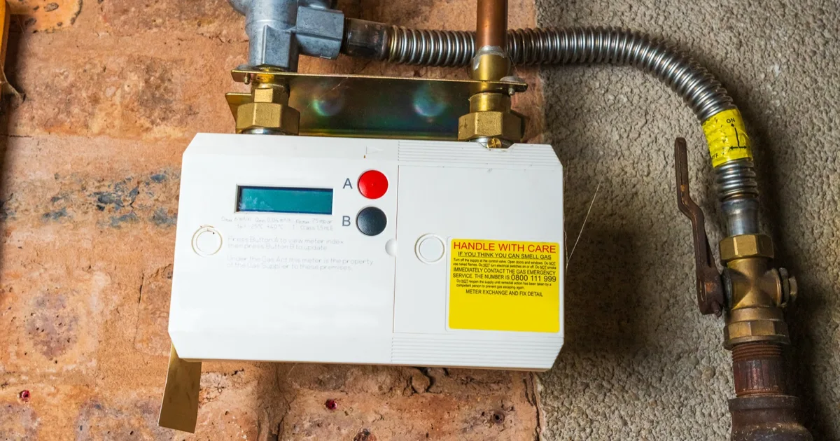 Close-up of a gas meter mounted on a brick wall.