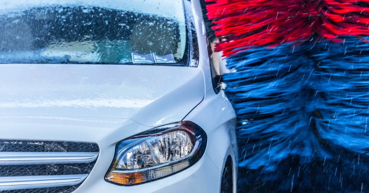 Close-up of an automated car wash brush passing over a car headlight.