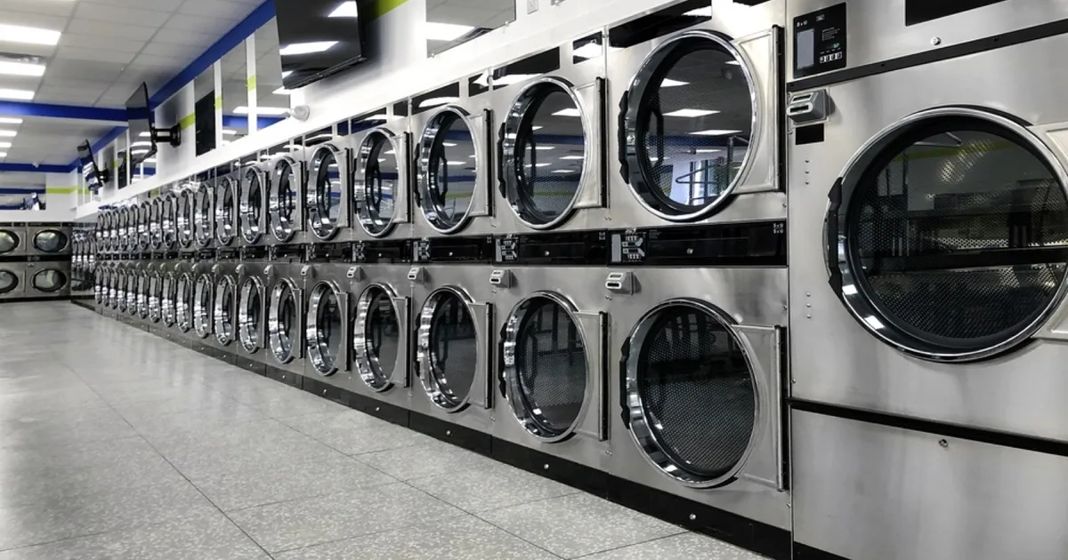 Row of stainless steel industrial dryers in a commercial laundrette.