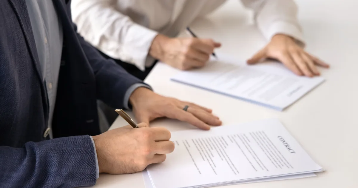 Close-up of two people signing a business energy contract.