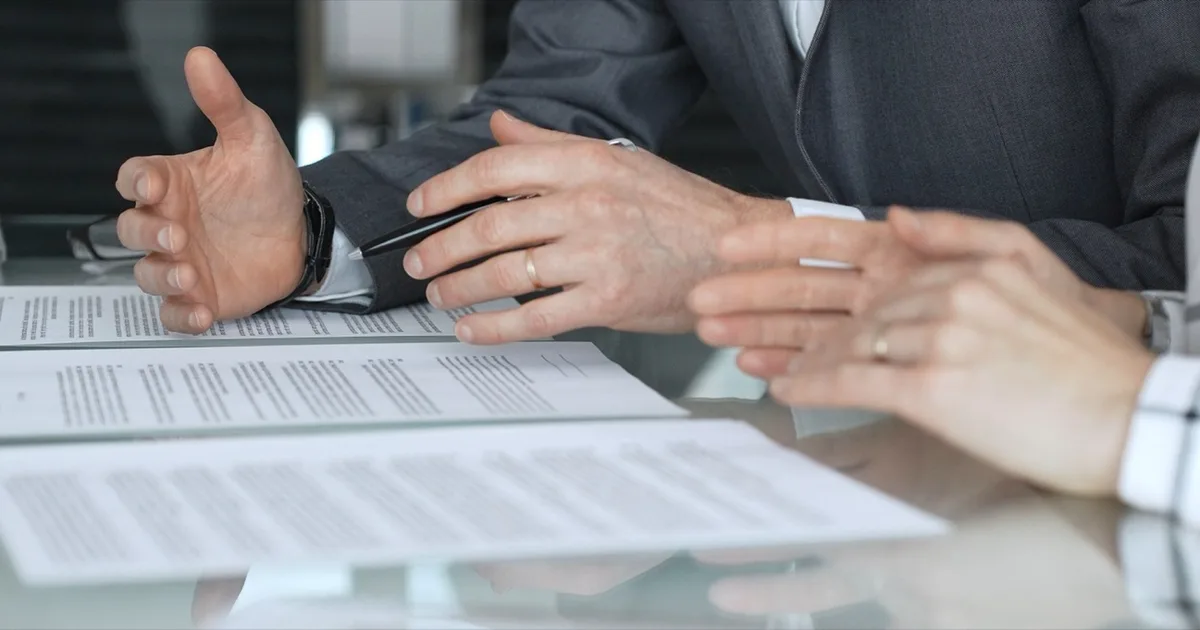 Hands of business people discussing a contract at a meeting table.