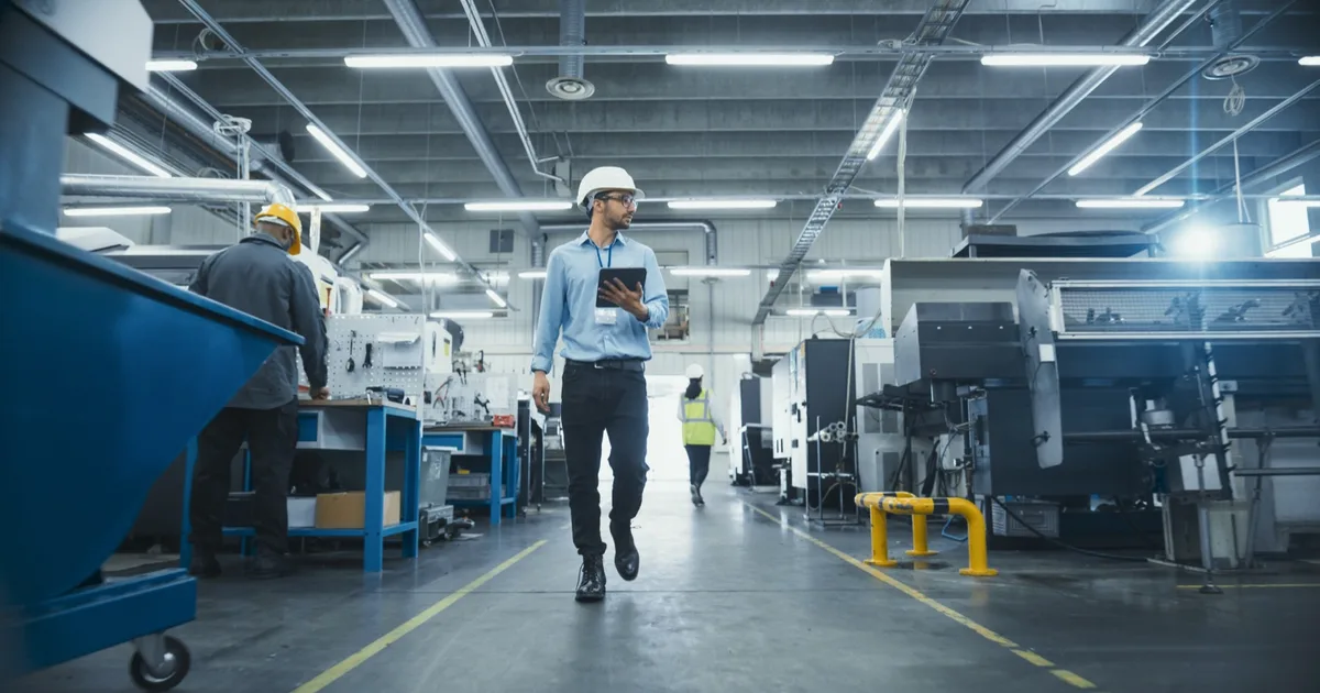 Factory manager with a tablet walking the production floor.