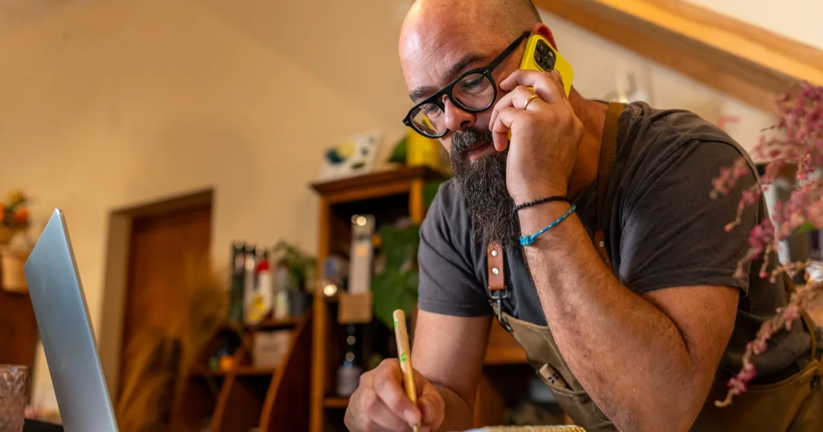 Small business owner on the phone taking notes in a workshop.