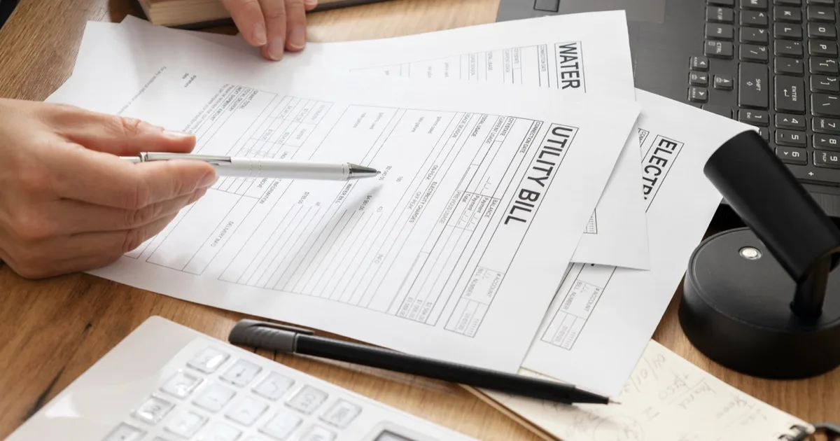 Utility bills being reviewed at a desk with a pen.