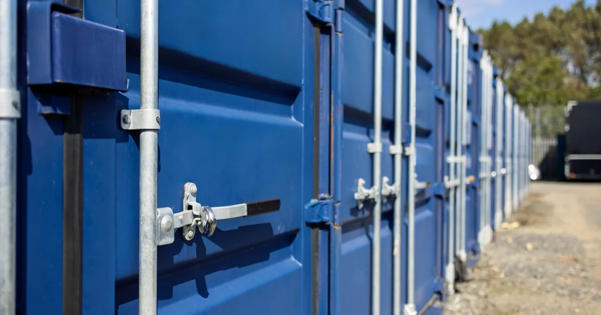 Blue shipping containers in a commercial storage yard.
