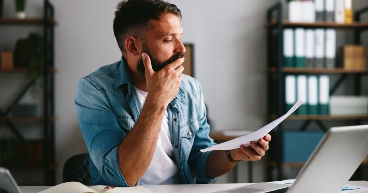 Businessman thoughtfully reviewing a paper energy bill.