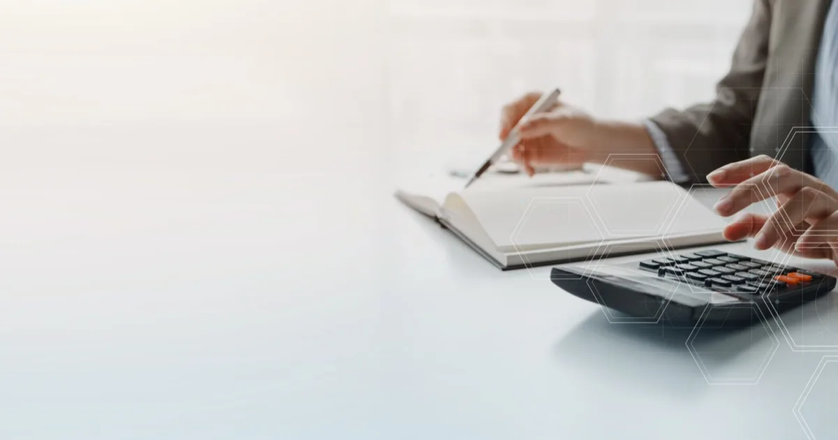 Businesswoman working with a calculator and notebook at a desk.