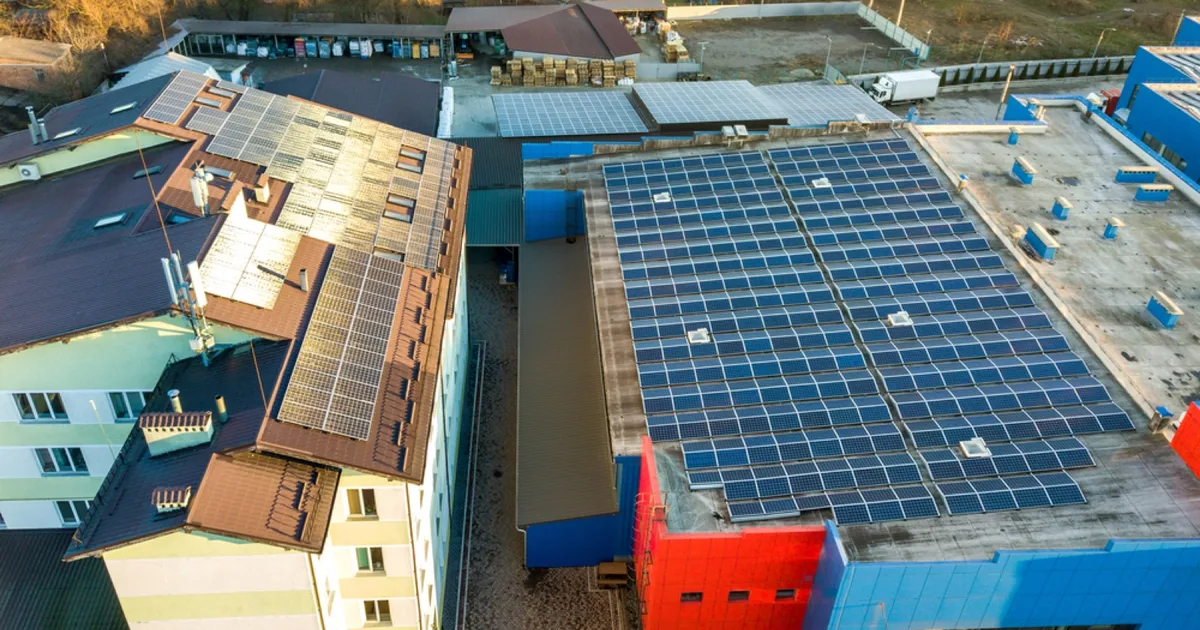 Aerial view of solar panels on an industrial building rooftop.