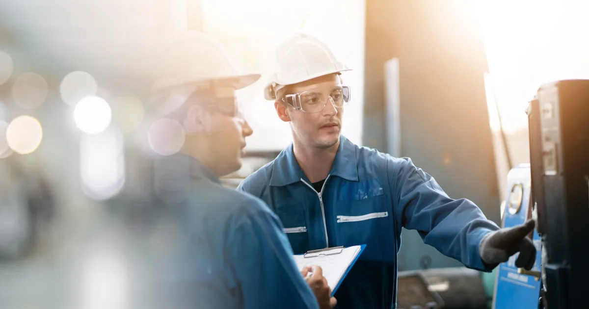 Factory engineers in hard hats inspecting production equipment.