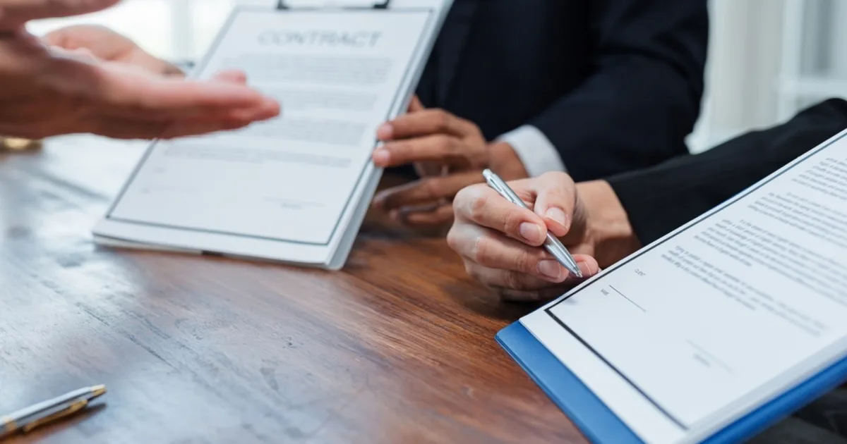 Business people reviewing a contract with a handshake gesture.